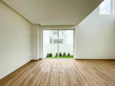 Spacious modern living room with wooden flooring and large glass doors opening to a private garden.