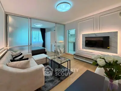 Modern living room with elegant decor and cozy seating area, featuring a sleek TV setup and stylish lighting.