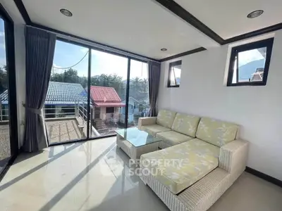 Bright living room with large windows and scenic view, featuring modern wicker furniture and elegant decor.