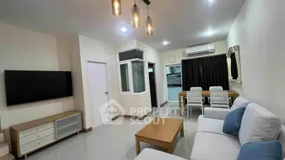 Modern living room with sleek furniture and open layout, featuring a large TV and dining area.