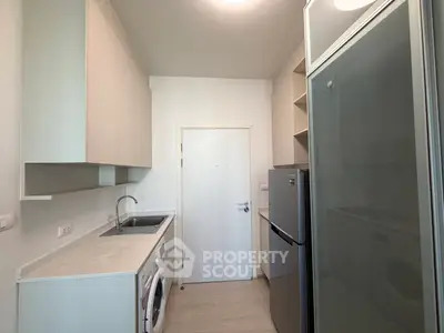 Modern compact kitchen with washing machine and fridge in a sleek apartment.