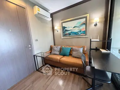 Cozy living room with leather sofa, wall art, and modern desk setup.