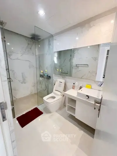 Luxurious modern bathroom with marble walls and glass shower enclosure