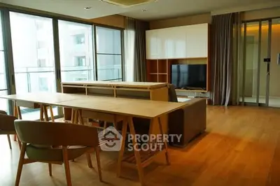 Spacious modern living room with large windows and elegant wooden flooring.