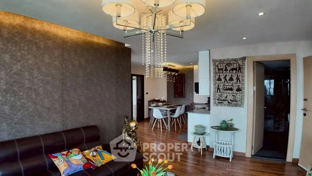Stylish living room with modern chandelier and open dining area, featuring elegant decor and wooden flooring.