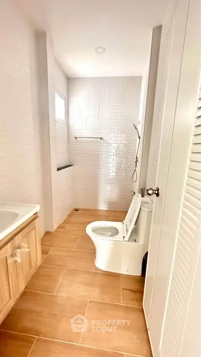 Modern bathroom with wooden flooring and sleek white fixtures
