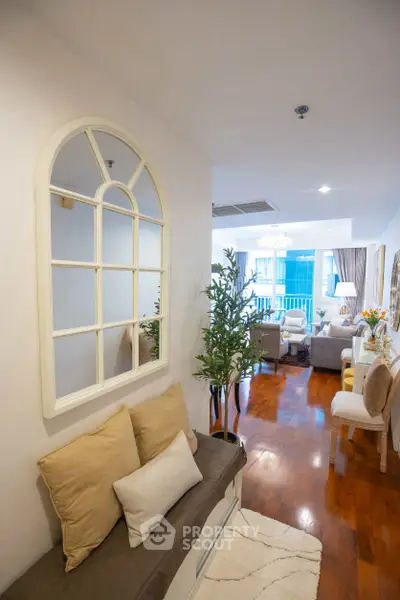 Spacious living room with elegant decor and wooden flooring, featuring a cozy seating area and large windows.