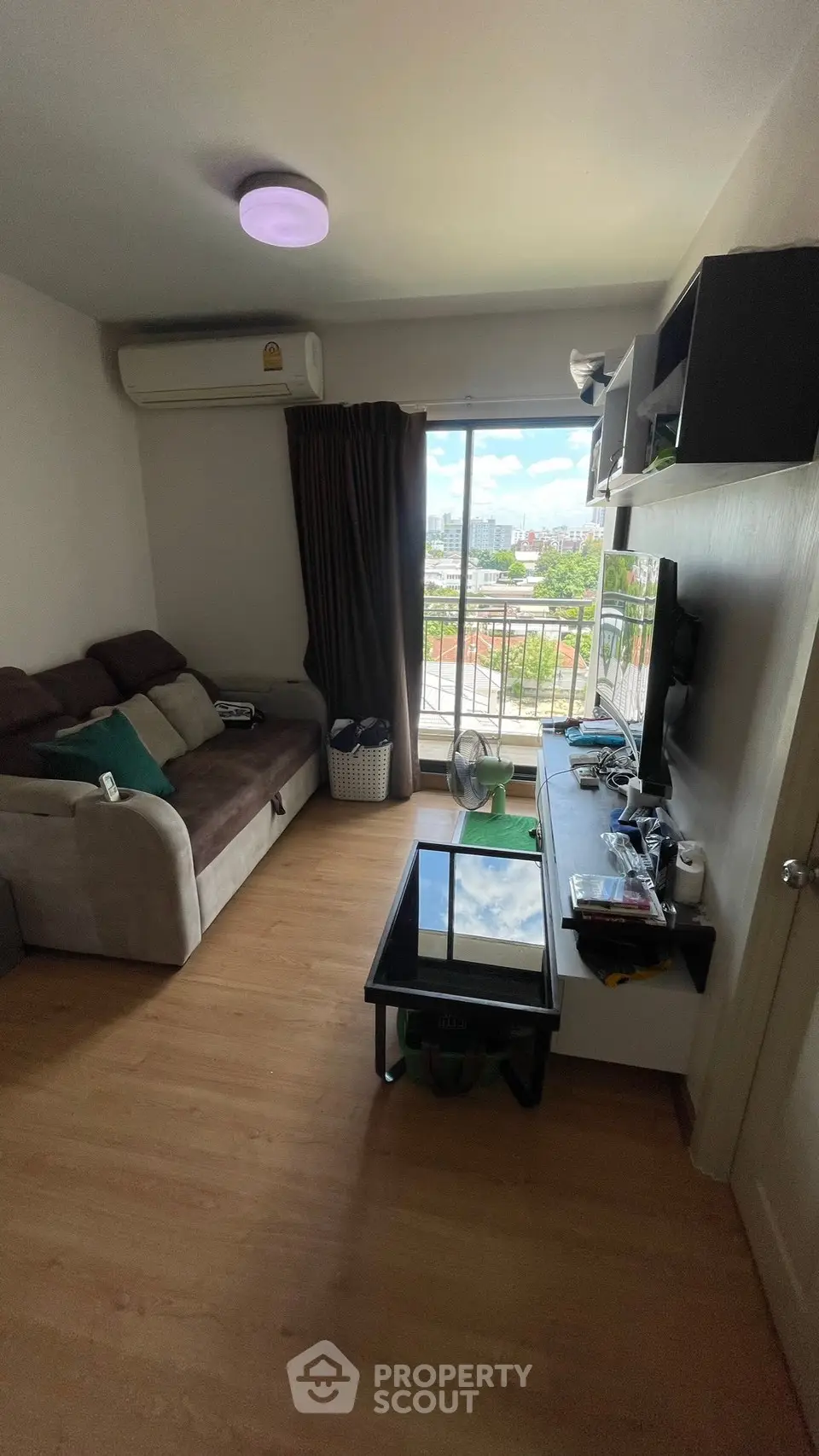 Cozy living room with city view, featuring a comfortable sofa, modern TV setup, and balcony access.