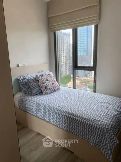 Cozy bedroom with city view and stylish bedding in modern apartment.