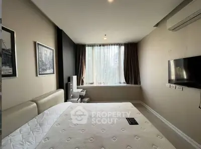 Modern bedroom with large window and wall-mounted TV in a stylish apartment.