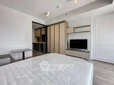 Modern bedroom with sleek furniture and open kitchen layout in a stylish apartment.