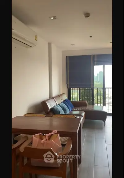 Modern living room with stylish furniture and city view balcony in a high-rise apartment.