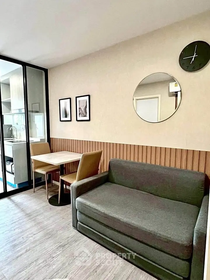Modern living room with stylish decor and compact dining area, featuring a cozy sofa and elegant wall art.