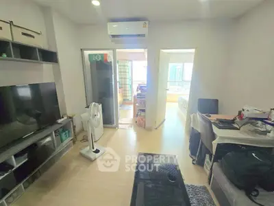 Modern living room with TV, air conditioning, and open layout leading to bedroom.