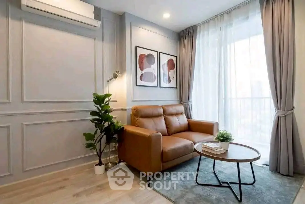 Stylish living room with modern decor, leather sofa, and natural light from large window.