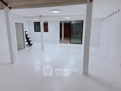 Spacious white basement with modern lighting and large windows, ideal for storage or creative space.