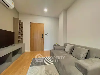 Modern living room with sleek gray sofa and stylish TV unit in a cozy apartment.