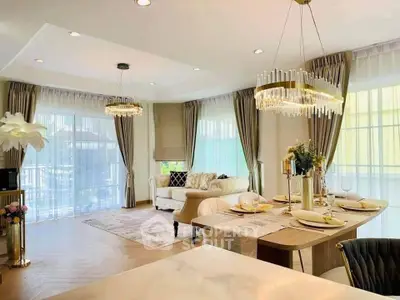 Luxurious open-plan living and dining area with elegant chandeliers and large windows.