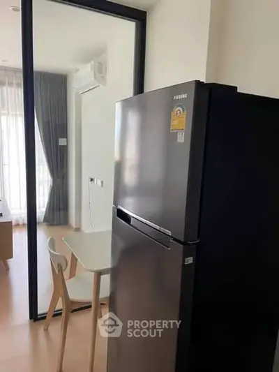 Modern kitchen with sleek fridge and dining area in stylish apartment.