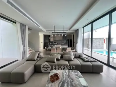 Luxurious open-plan living room with modern kitchen and pool view