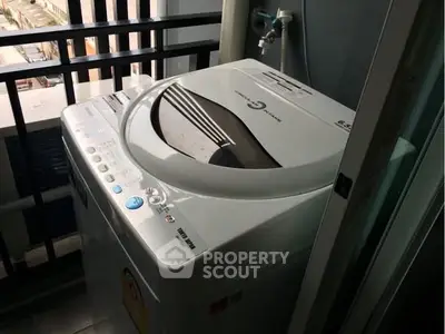Compact balcony with washing machine and city view, ideal for urban living.