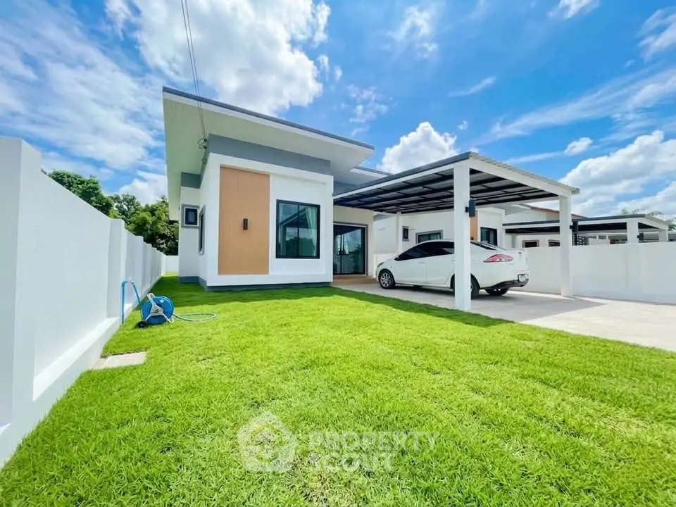 Modern single-story house with carport and lush green lawn under a clear blue sky.