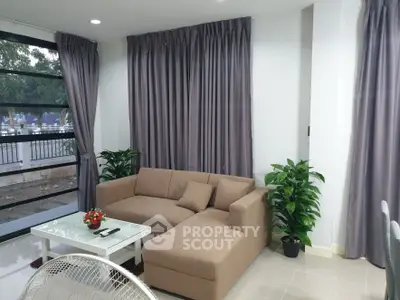 Modern living room with cozy sofa and large windows, perfect for relaxation.