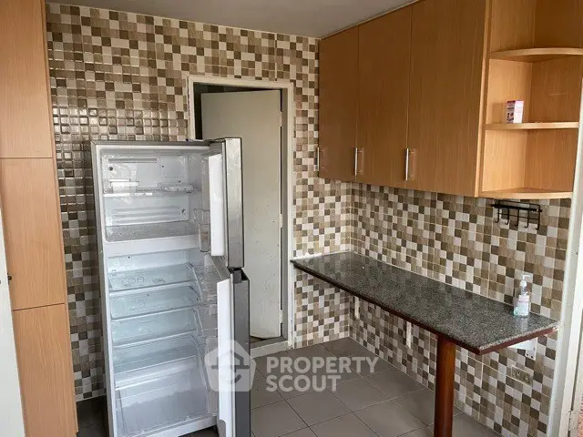 Modern kitchen with open fridge and stylish tile backsplash
