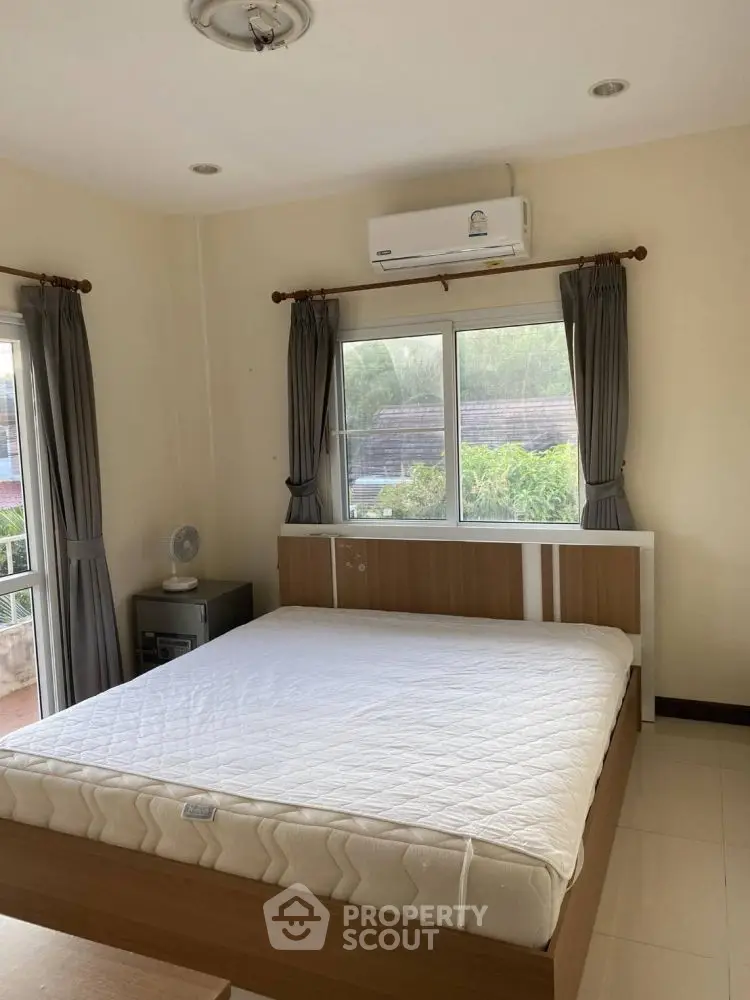 Cozy bedroom with large window and air conditioning, perfect for comfortable living.
