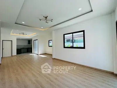 Spacious open-plan living room with modern kitchen and elegant lighting in a bright, airy home.