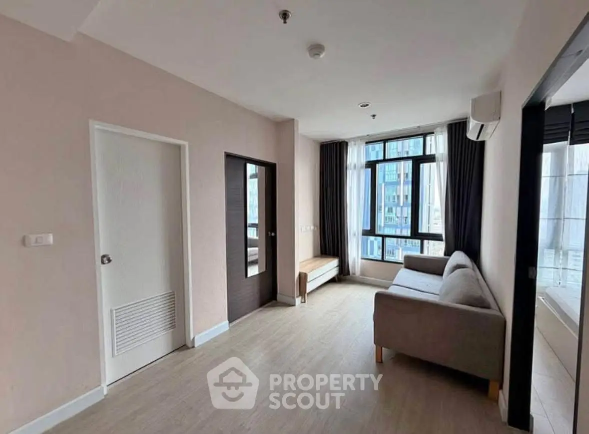 Spacious modern living room with large windows and stylish sofa in urban apartment.