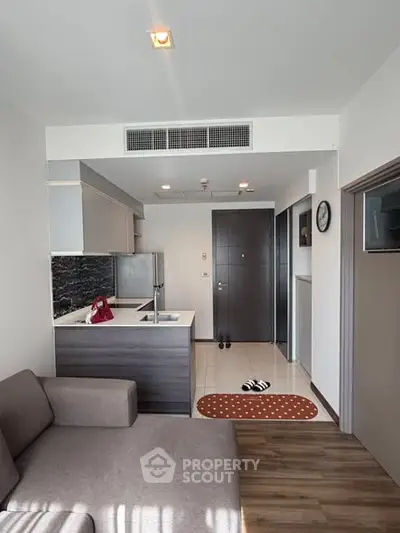 Modern open-layout living room with kitchen in a stylish apartment, featuring sleek furniture and contemporary design.