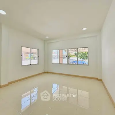 Spacious and bright living room with large windows and tiled flooring, perfect for modern living.