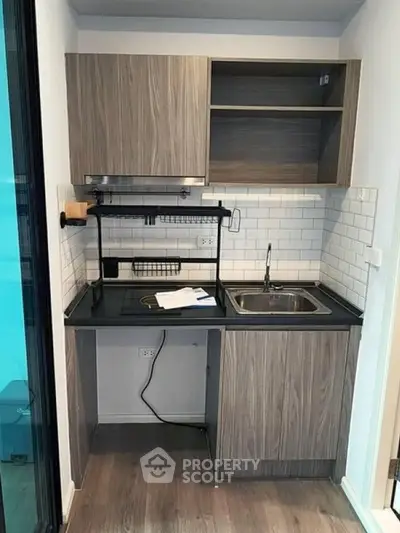 Modern compact kitchen with sleek cabinetry and tiled backsplash in urban apartment.