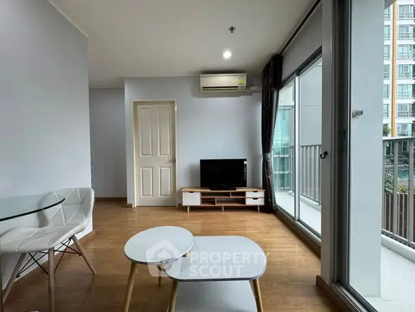 Modern living room with balcony view and sleek furniture in a high-rise apartment.