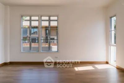 Spacious empty room with large windows and wooden flooring, perfect for customization.