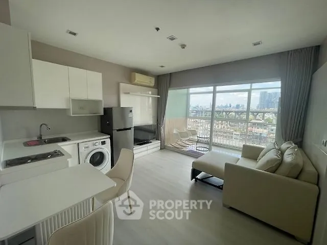 Modern open-plan living room with city view, featuring sleek kitchen and cozy seating area.