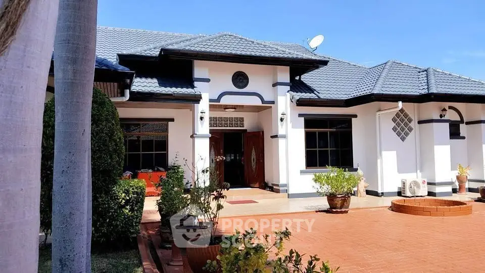 Charming single-story home with blue-tiled roof and spacious front patio, perfect for family living.