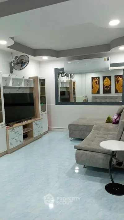 Modern living room with stylish furniture and entertainment center, featuring a cozy sectional sofa and wall-mounted TV.