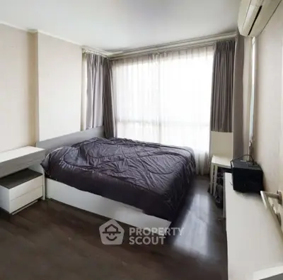 Cozy bedroom with modern furnishings and large window for natural light.