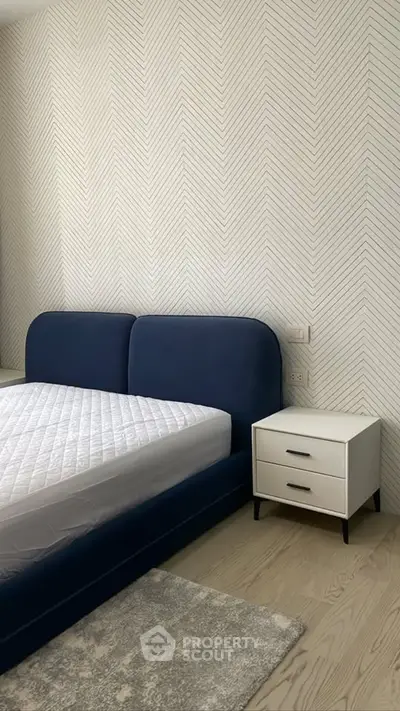 Modern bedroom with stylish blue bed and chevron wallpaper