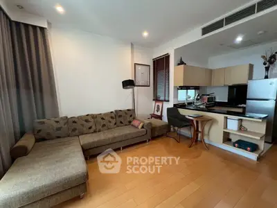 Modern living room with open kitchen, featuring a cozy L-shaped sofa and sleek wooden flooring.