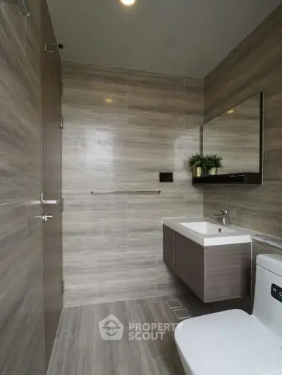 Modern bathroom with sleek fixtures and elegant wood paneling, featuring a wall-mounted sink and toilet.