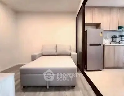 Modern studio apartment with cozy sofa bed and sleek kitchen area.
