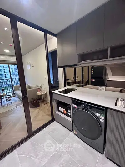 Modern kitchen with sleek appliances and open layout leading to stylish living room.