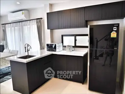 Modern kitchen with sleek black cabinets and stainless steel appliances.