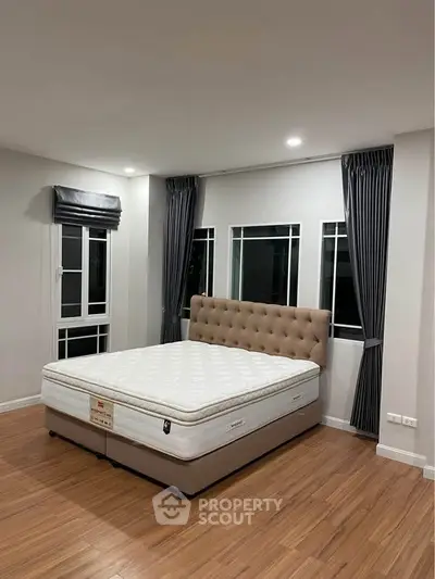 Spacious bedroom with elegant bed and large windows, perfect for natural light lovers.