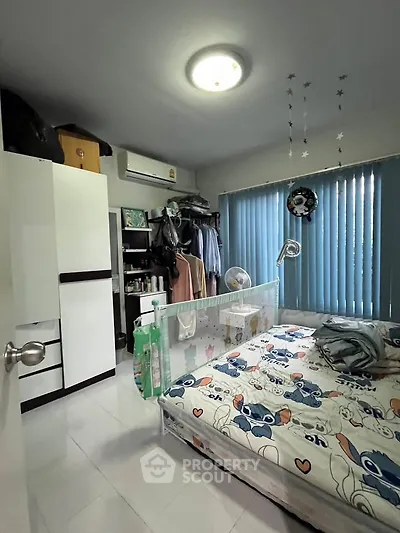 Cozy bedroom with modern decor and ample storage space, featuring a playful bedspread and natural light.