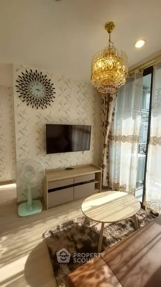 Charming living room with elegant chandelier and modern decor, featuring a wall-mounted TV and stylish furniture.