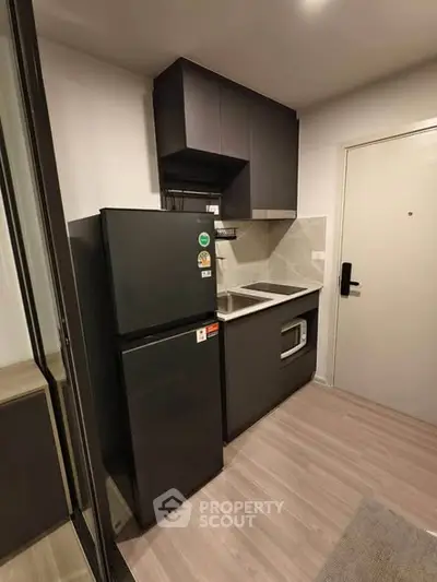 Modern compact kitchen with sleek black appliances and minimalist design